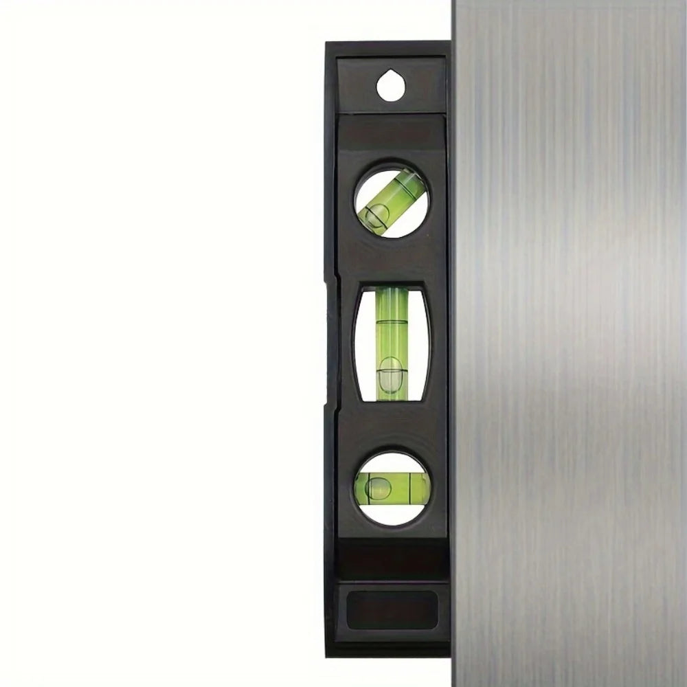 A vertical black magnetic torpedo level with three measurement markings for precision measuring.