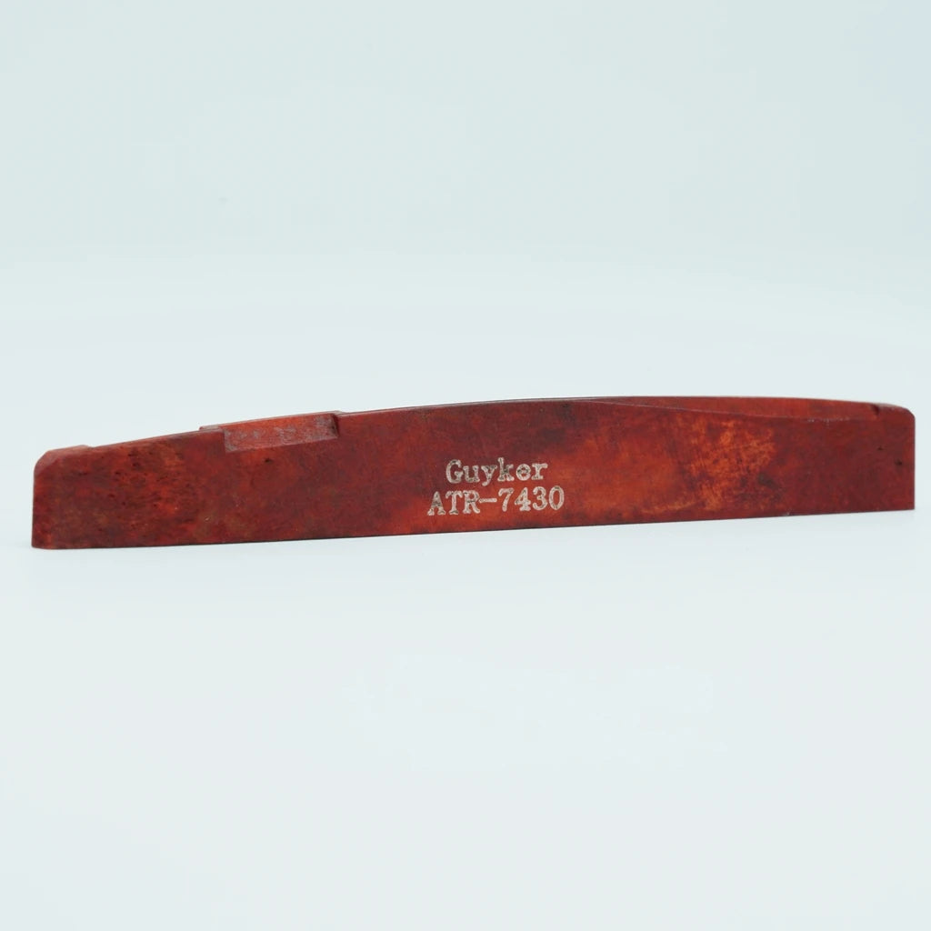 A piece of reddish-brown acoustic guitar bone bridge saddles labeled Guyler ATR-7430