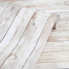 A close-up of white distressed wood grain self-adhesive wall stickers placed on a light wooden surface.