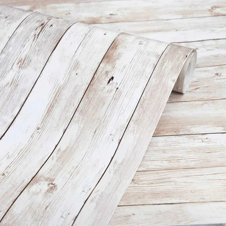 A close-up of white distressed wood grain self-adhesive wall stickers placed on a light wooden surface.