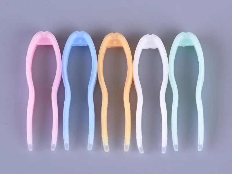 A set of five colored plastic tools for handling contact lenses, arranged in a row.