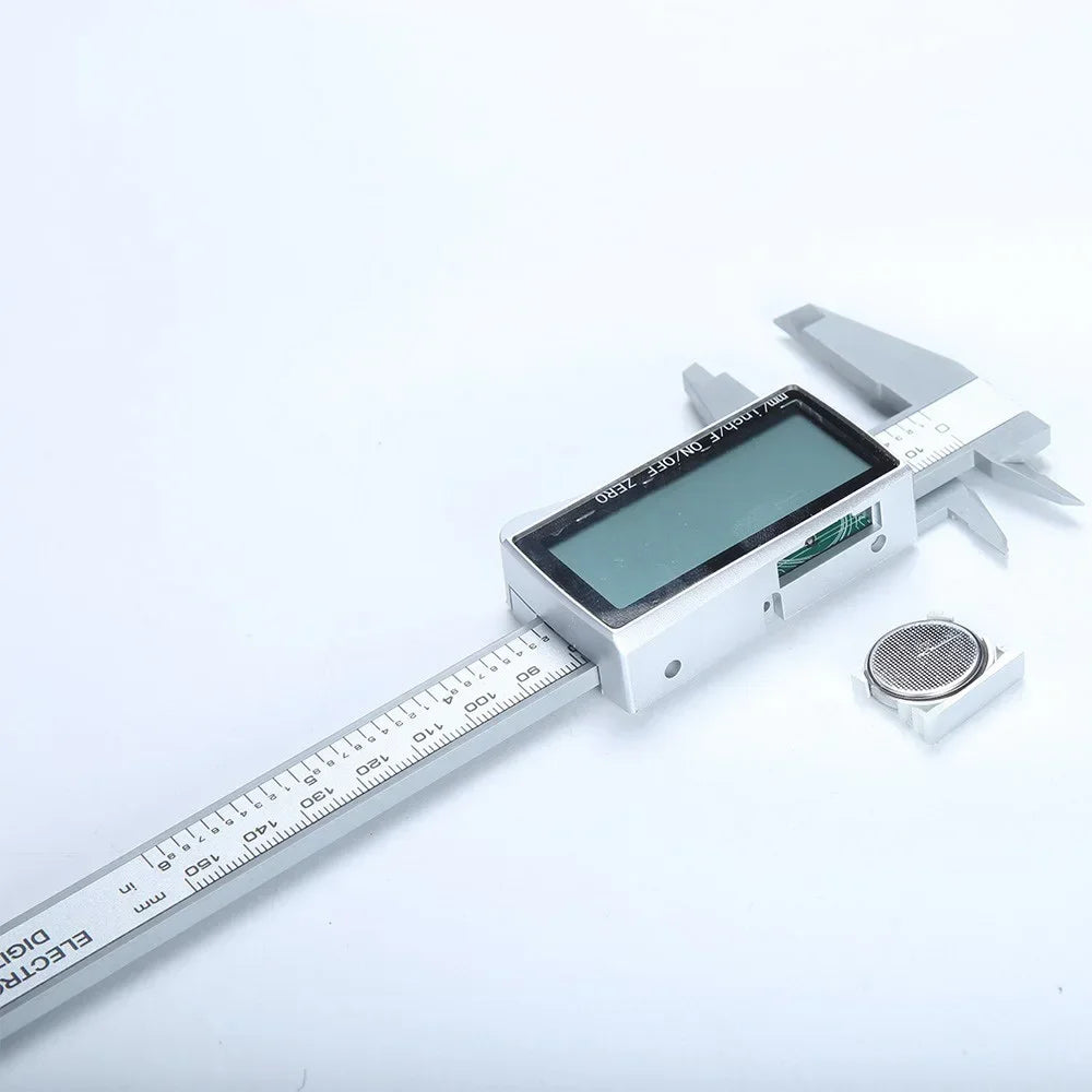Calibrador digital vernier plateado con pantalla y escala de medición negra sobre fondo blanco.