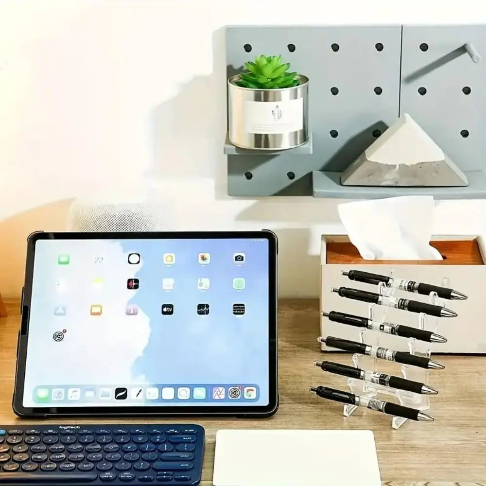 A transparent ballpoint pen holder organizer with black pens displayed on a wooden desk.