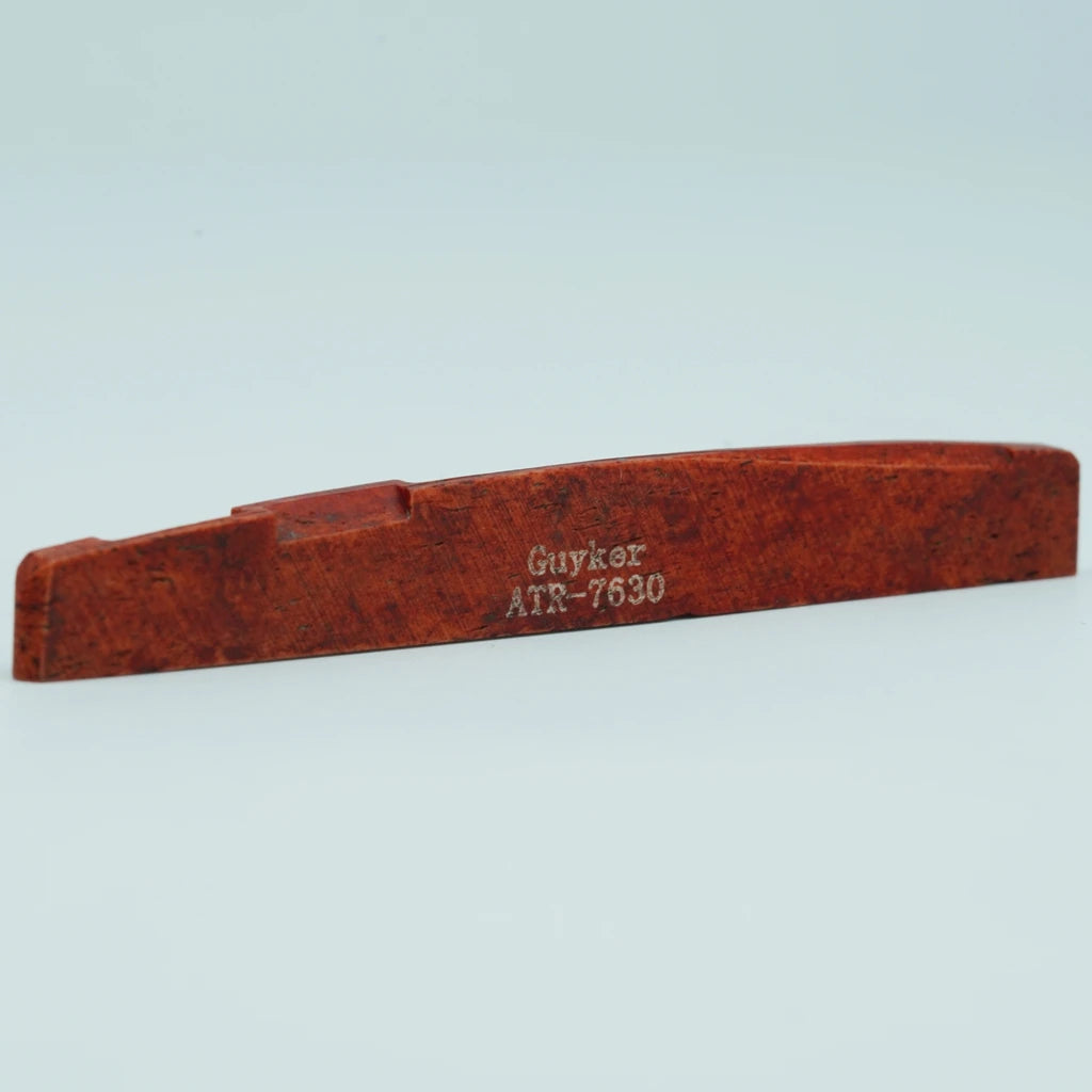 A wooden guitar bone bridge saddle with the inscription Guykör ATR-7630