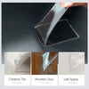 A hand is peeling a piece of clear acrylic tape from a dark surface, showing its thickness and transparency.