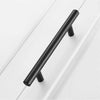 A long, black stainless steel kitchen door pull handle mounted on a white cabinet door.