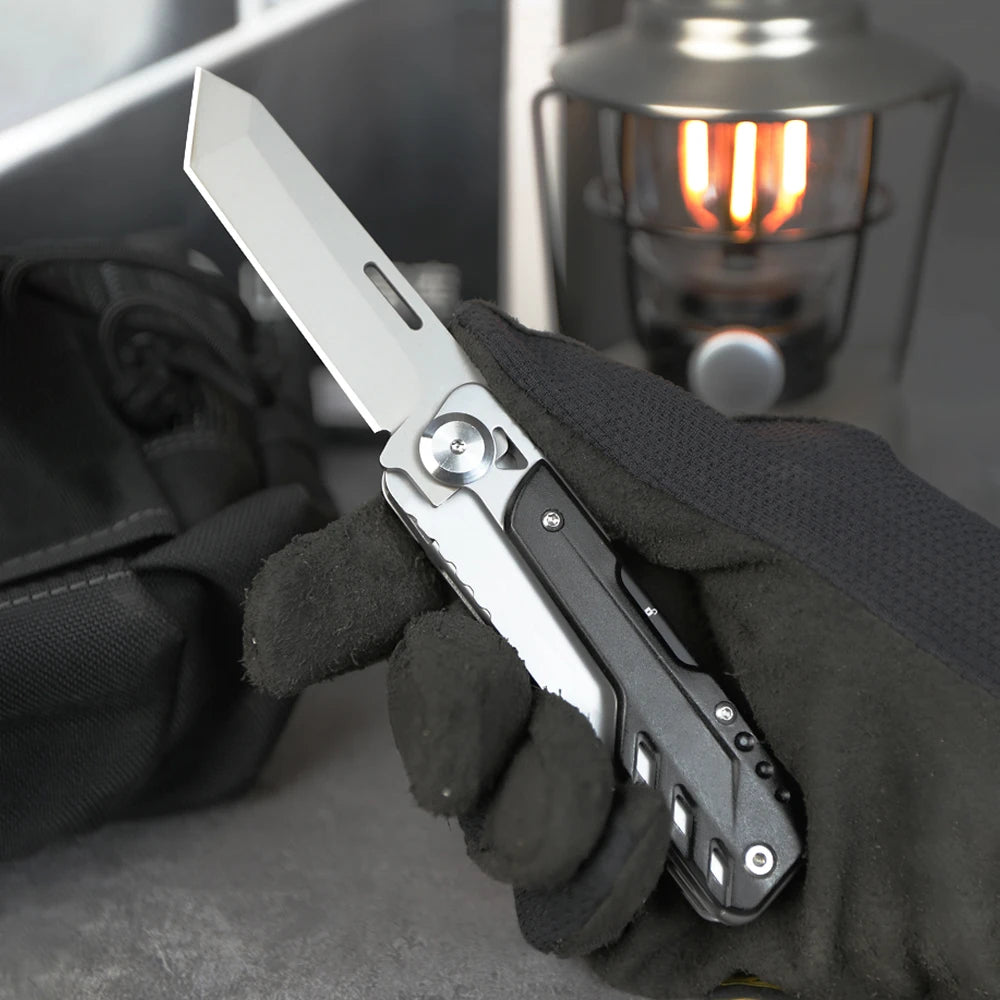 A hand wearing a black glove holds a silver compact multi-tool pocket knife set against a dark background.