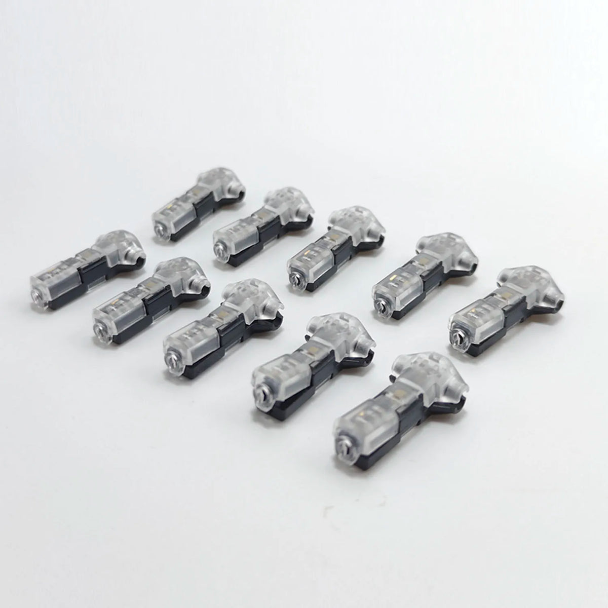 A collection of small, gray T-type wire splice connectors arranged on a white background.