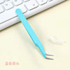 A light blue precision crafting tweezers set lying on a white keyboard surface.