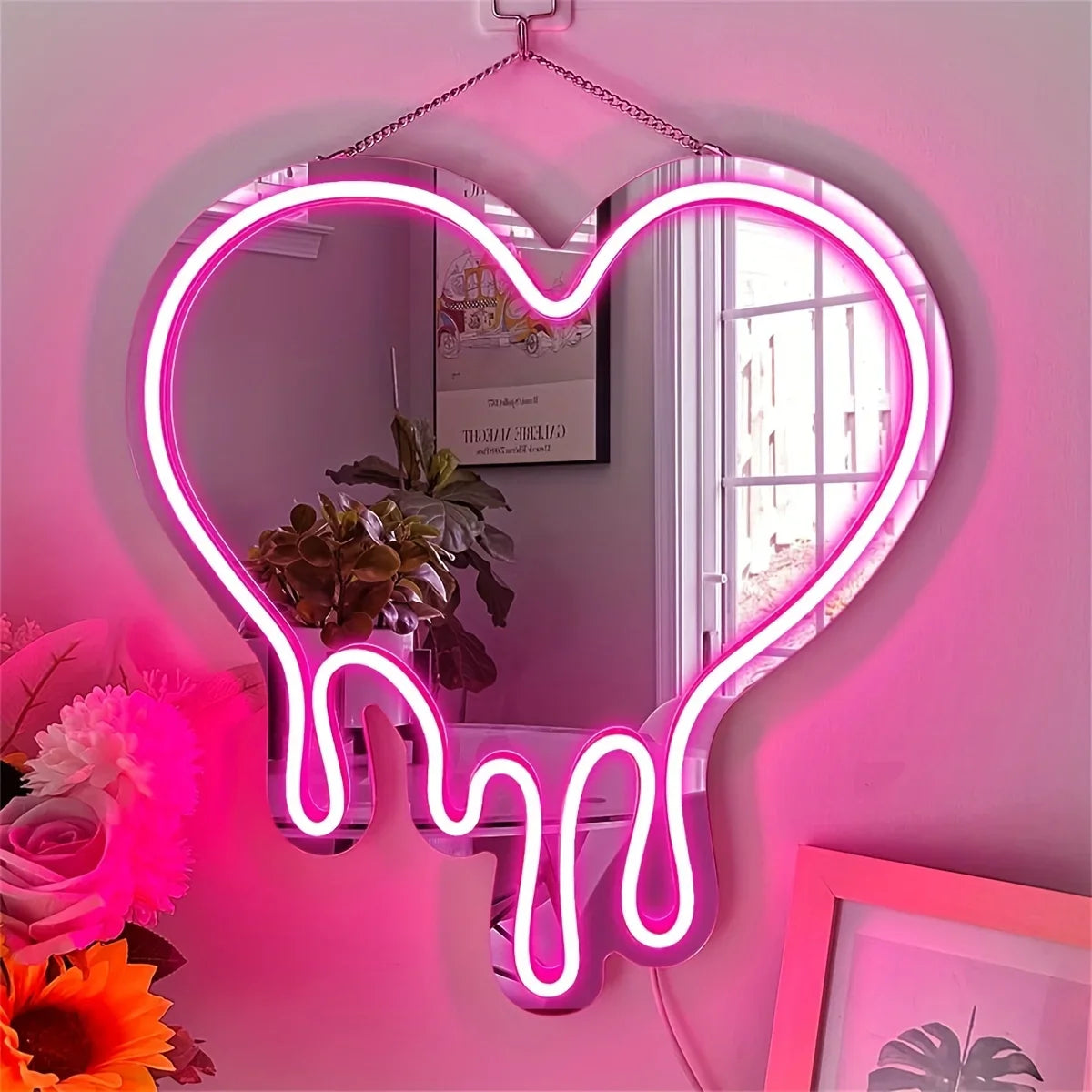 Herzförmiges Neon-Schild mit Tropfeffekt beleuchtet einen Spiegel an einer rosa Wand.
