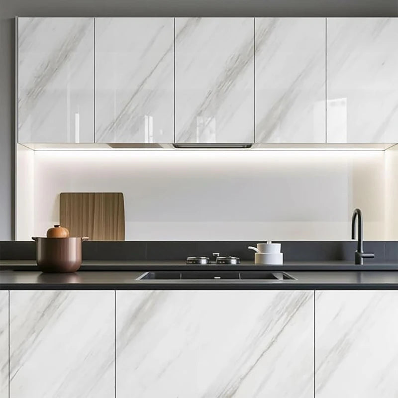 Modern kitchen cabinet and countertop featuring white marble-patterned doors and a dark gray surface.