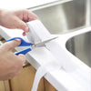Des mains utilisent des ciseaux pour couper un rouleau de ruban adhésif scellant en PVC transparent pour cuisine ou salle de 