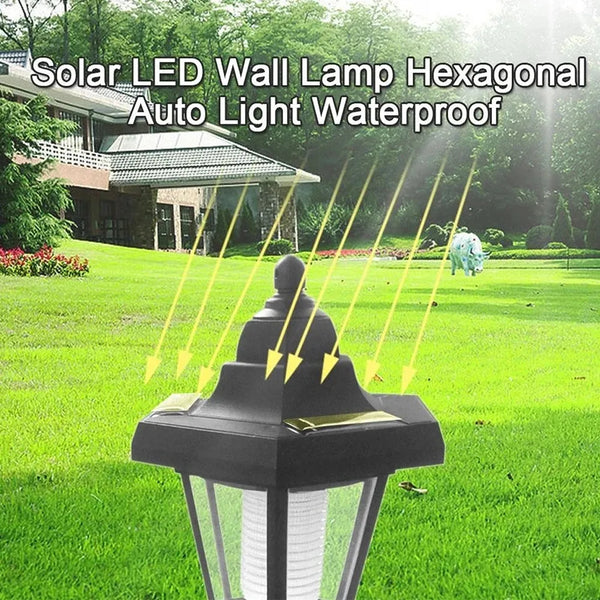 A black hexagonal solar LED wall lamp fixture shining light onto a green lawn.