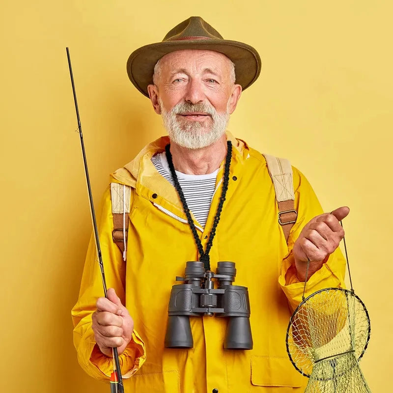 Ein älterer Mann mit breitermütigem Hut und gelbem Jacke hält eine Angelrute und ein Fernglas.