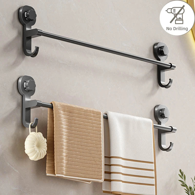 A silver adhesive towel rack mounted on a wall, holding folded beige and white towels.