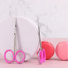 A pair of professional stainless steel nail cuticle trimmers with pink handles resting on a white plate.