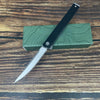 A folding utility knife with a black handle and silver blade rests on a green wooden box.