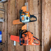 An orange and black metal chainsaw hook wall storage rack mounted on a wooden wall.