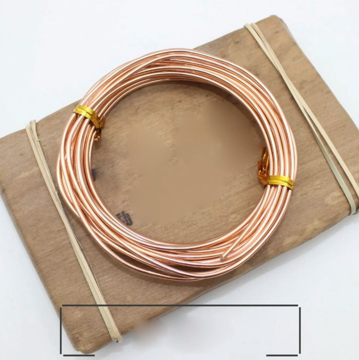 Spule roségold-anodierter Metall-Schmuckdraht auf Holzbrett mit dünnem Schnur.