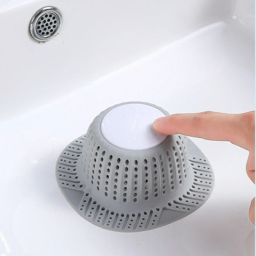 A gray collapsible bathtub drain hair catcher protector is shown being placed into a white sink.