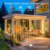 Outdoor curtain lights illuminating a stone patio area with comfortable seating and decorative plants