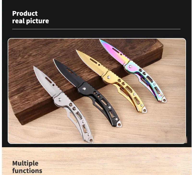A collection of four stainless steel folding keychain knives in various colors and finishes displayed on a wooden surface.