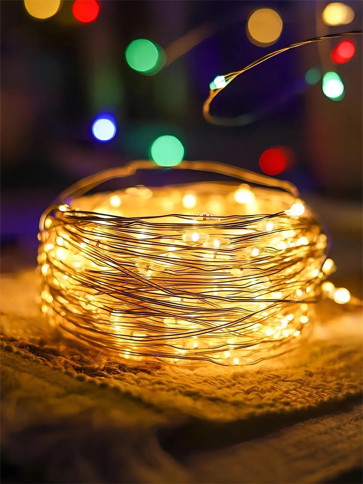Sphère lumineuse de guirlande de fils de cuivre blanc chaud sur une surface texturée avec des lumières bokeh floues en arrièr