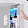 A close-up of a white refrigerator door with a safety lock installed, showing the interior and a hand interacting with the la