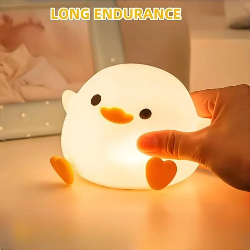 Eine Hand hält eine leuchtende weiße Silikon-Enten-Nachtleuchte auf einer Holzoberfläche.