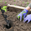 A hand wearing a purple glove is using a garden auger to create a hole in the soil for planting a seedling.