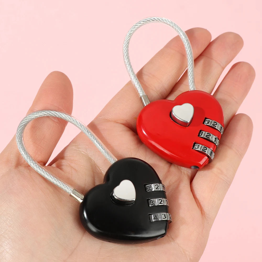 A hand holds a red and black heart-shaped combination lock with silver wires.