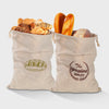 A beige linen drawstring bag filled with various baked goods like bread rolls and buns.