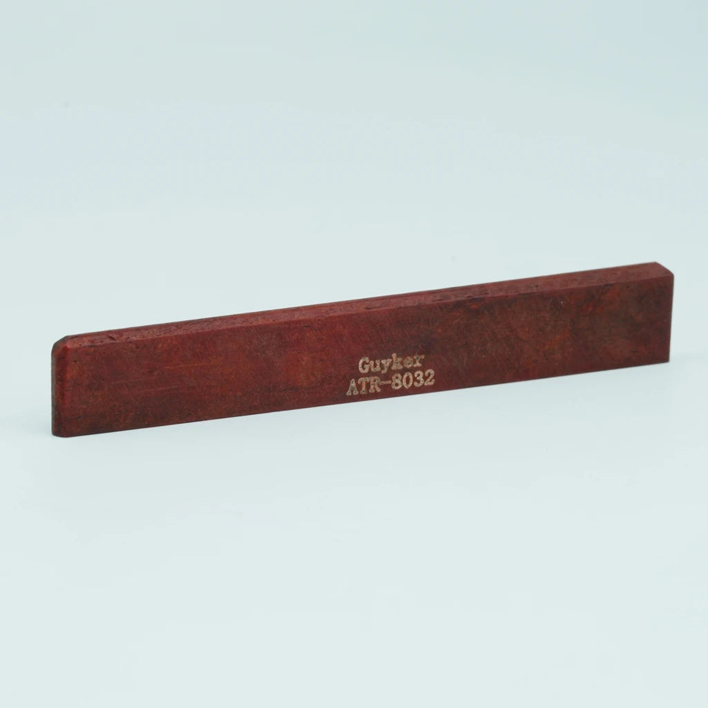 A wooden guitar bone bridge saddle with the text Guyker ATR-8032 engraved on it.