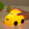 A hand holds a yellow silicone night light shaped like a taxi with the word TAXI on it.