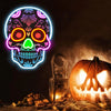 A glowing neon skull sign with colorful internal lights floats above a carved pumpkin and autumn leaves.