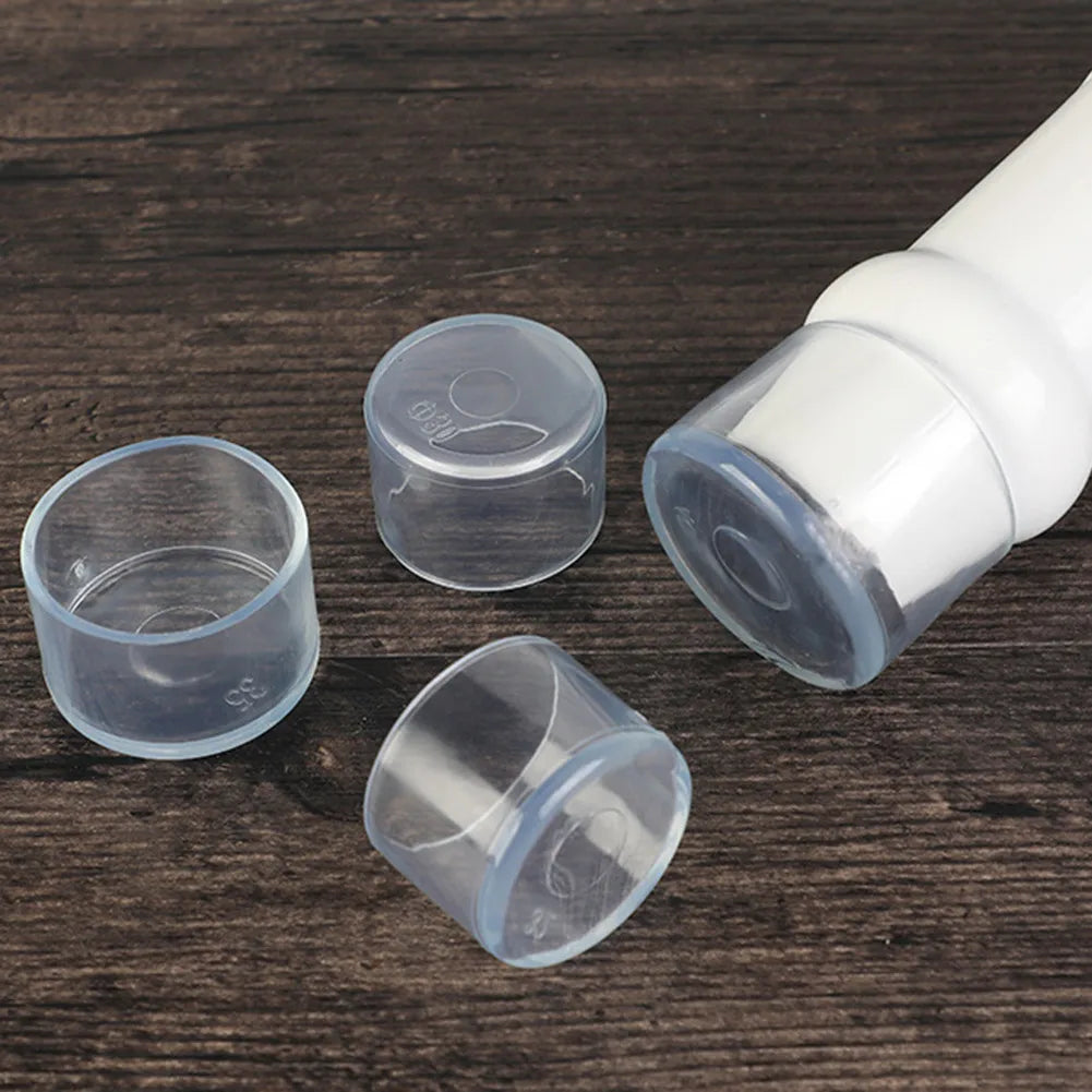 Clear plastic furniture leg foot protectors and a white plastic cap on a dark wooden surface.