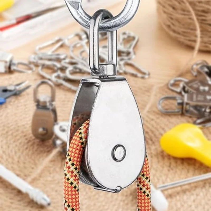 A stainless steel wire rope pulley block with a metal hook and braided cord is shown on burlap.