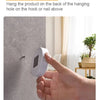 A hand is placing a white automatic motion sensor night light onto a wall surface for installation.