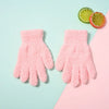 Pair of pink plush full finger winter gloves for kids resting on a light blue surface next to a lime and orange slice.