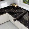Black marble contact paper installed on a kitchen countertop with white cabinets and a window view.
