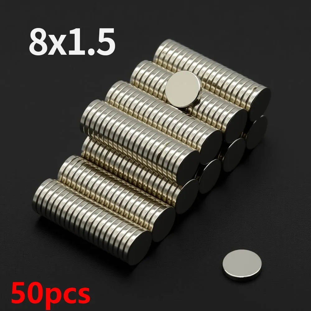 A pile of 50 fridge magnets, 8 sets of 1.5 magnets each, stacked diagonally on a dark surface.