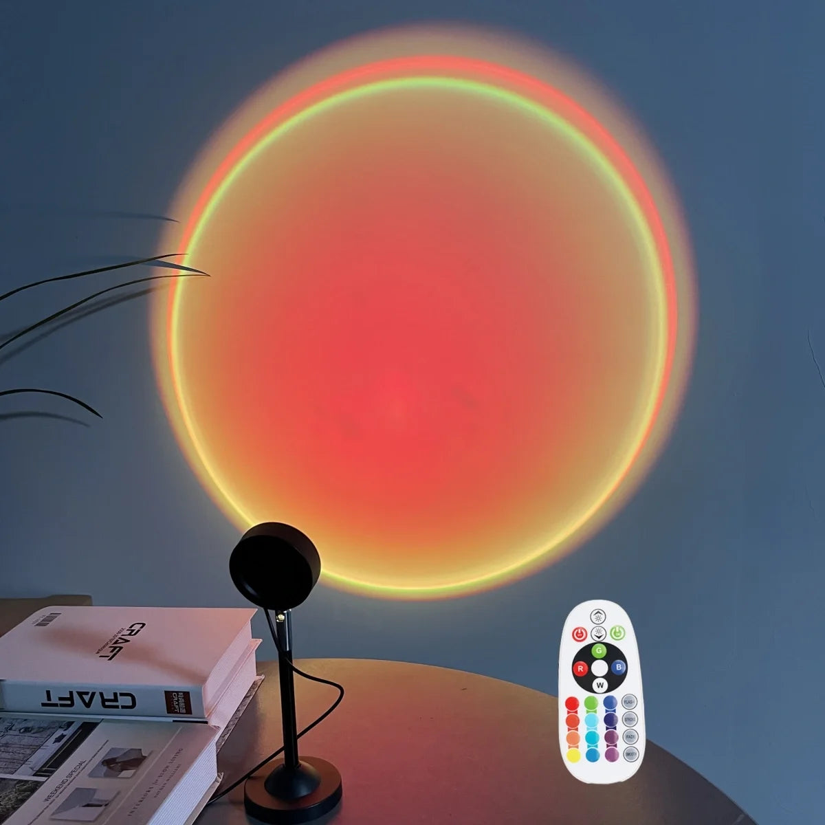 A USB sunset projection light is shown illuminating a wall with a bright orange and red glow, next to a remote control.