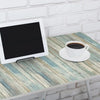 Ein weißes Tablet mit dunklem Bildschirm liegt auf einem Holztable neben einer weißen Kaffeetasse.
