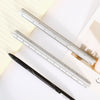 A close-up of a black pen and a silver aluminum triangular ruler resting on lined paper.