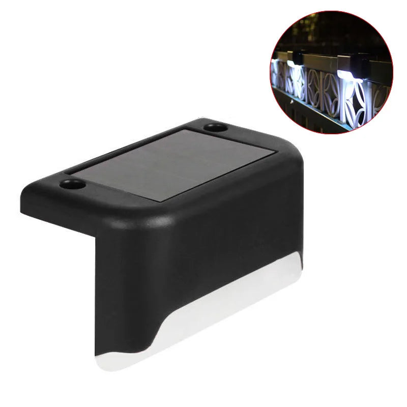 Schwarze Solarlampe mit klarem Objektiv, gezeigt neben einem Ausschnitt der Beleuchtung eines Geländers