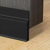 A black door draft stopper weather stripping seal installed on a wooden door frame.