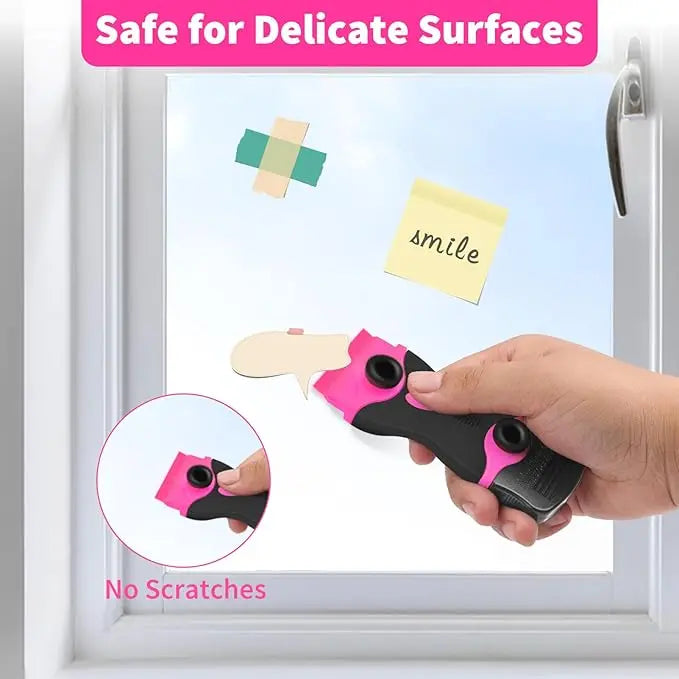 A hand uses a pink adhesive remover scraper on a window to clean a surface, demonstrating it is safe for delicate surfaces.