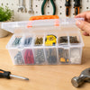 A hand holds a transparent multi-compartment tool storage box filled with various colored and textured tools.