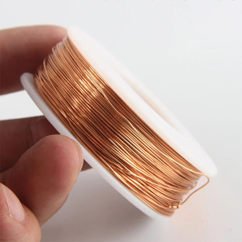 A hand holds a coil of high-conductivity bare copper wire wrapped in white plastic.
