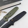 A folding utility knife with a green handle and black blade is displayed next to a book.